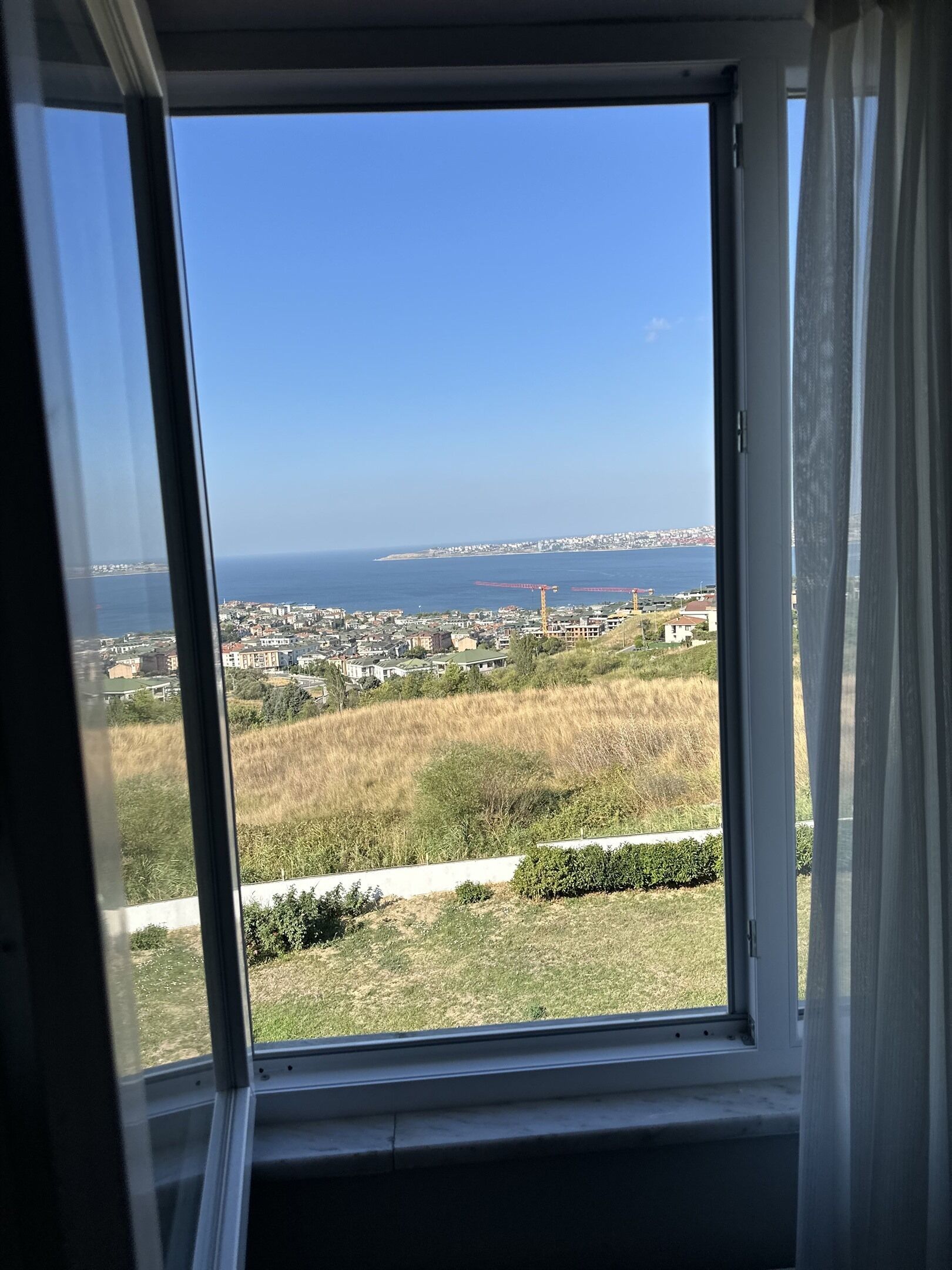 Una ventana con vistas a un pueblo costero, incluyendo edificios y una masa de agua.