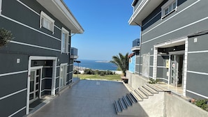 Un edificio con vista al mar, un espacio al aire libre cubierto y una escalera que lleva a un nivel superior.
