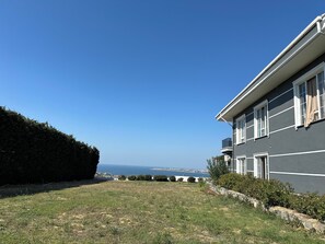Un edificio residencial con vista al mar, un césped cuidado y un seto.