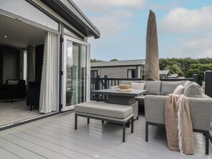 Ein moderner Außenbereich mit Sofa, Tisch und Stühlen, einem überdachten Bereich und Blick auf die umliegende Nachbarschaft.
