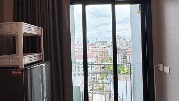 Eine kleine, moderne Küche mit Mikrowelle, Kühlschrank und Blick auf eine Stadtlandschaft durch eine Glastür.