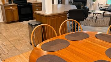 Een eethoek met een houten tafel en stoelen, omringd door keukenkasten en een televisie.