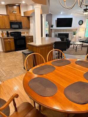 Un comedor con mesa y sillas de madera, rodeado de armarios de cocina y un televisor.