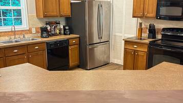 A modern kitchen with wooden cabinets, stainless steel appliances, and a central island with seating.