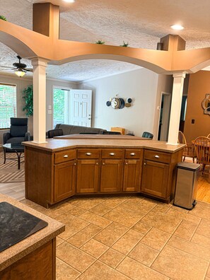 Una cocina con una isla curva, armarios de madera y piso de baldosas.