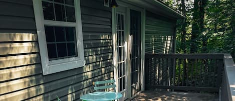A wooden deck with a table and chairs, a door, and a window.