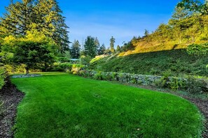 A well-maintained lawn with a stone retaining wall and a variety of trees. - Gorge Retreat | Panoramic Views & Private Trail (Stevenson)
