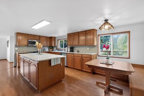 A modern kitchen with wooden cabinets, a central island, and a large window.