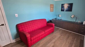 A room with a red sofa, a dark wooden cabinet, and a blue wall. - Spacious & Classy Home for Extended Stays (Houston)