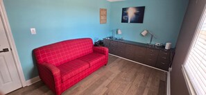 Una habitación con un sofá rojo, un aparador de madera oscura y una pared azul.