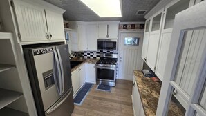 A kitchen with white cabinets, stainless steel appliances, a checkered backsplash, and a window above the sink. - Spacious & Classy Home for Extended Stays (Houston)