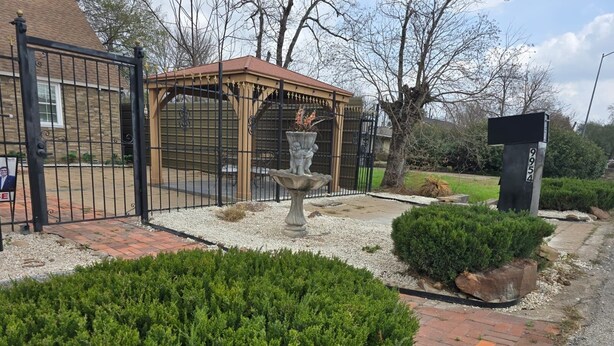 A gated entrance with a gazebo, a stone fountain, and well-maintained shrubbery. - Spacious & Classy Home for Extended Stays (Houston)