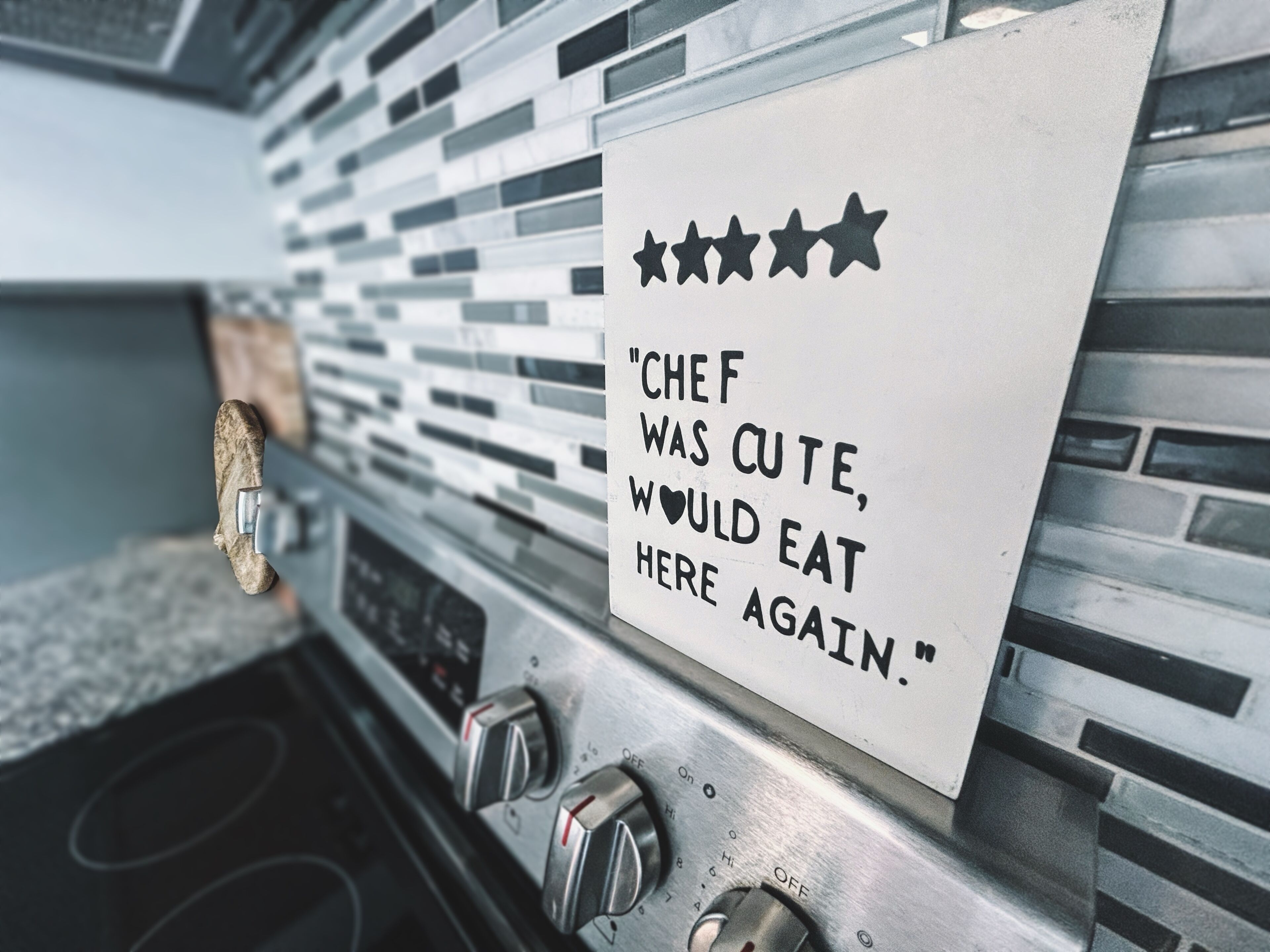 Een keukenhoek met een bord waarop staat: 'CHEF WAS CUTE, WOULD EAT HERE AGAIN'.