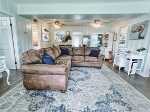 A living room with a large sectional sofa, a patterned rug, and a white console table.