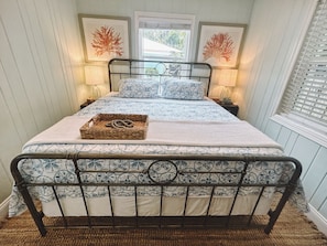 A bed with a metal frame, a patterned bedspread, and two wall-mounted lamps.
