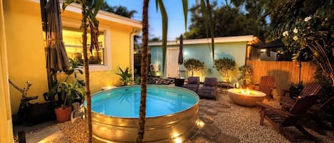 A backyard with a swimming pool, seating area, and potted plants.
