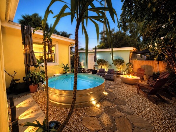 A backyard with a swimming pool, seating area, and potted plants.