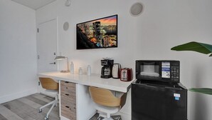 Une cuisine compacte équipée d’un four à micro-ondes, d’un grille-pain et d’une machine à café, le tout posé sur un plan de travail blanc.