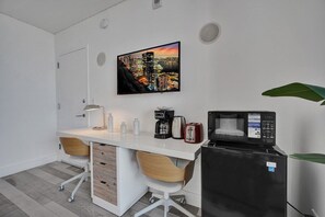 Eine kompakte Küche mit Mikrowelle, Toaster und Kaffeemaschine auf einer weißen Arbeitsplatte.