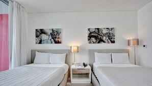 Une chambre d’hôtel avec deux lits, une table de chevet avec une lampe et des œuvres d’art accrochées aux murs.