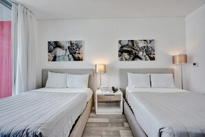 Ein Hotelzimmer mit zwei Betten, einem Nachttisch mit Lampe und Bildern an der Wand.
