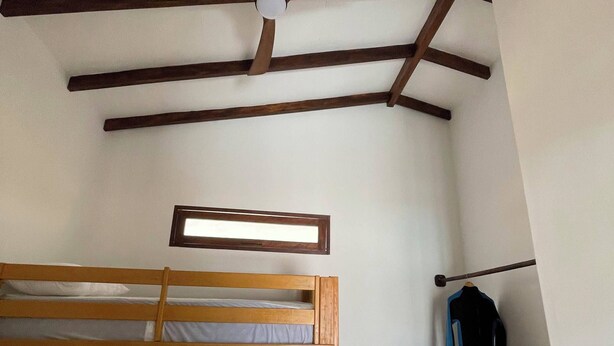 A room with a bunk bed, a ceiling fan, and a coat rack.
