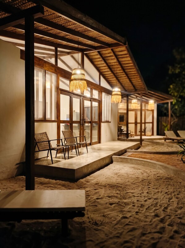 A covered outdoor seating area with tables and chairs, a pergola structure, and hanging lights.