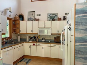 Eine Küche mit weißen Schränken, einer Mikrowelle und einem Kühlschrank.