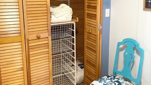 A wooden closet with a hanging rack, a small table, and a chair with a patterned cushion. - Sweet split level 4 bedroom house, quiet neighborhood, walking distance to beach (Kitty Hawk)