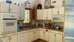 A kitchen with white cabinets, a microwave, a stove, and various kitchen utensils. - Sweet split level 4 bedroom house, quiet neighborhood, walking distance to beach (Kitty Hawk)