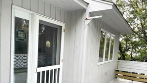 A white wooden building with a covered porch, a sliding glass door, and a white bench. - Sweet split level 4 bedroom house, quiet neighborhood, walking distance to beach (Kitty Hawk)
