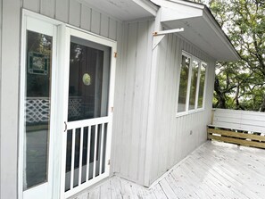 A white wooden building with a covered porch, a sliding glass door, and a white bench. - Sweet split level 4 bedroom house, quiet neighborhood, walking distance to beach (Kitty Hawk)