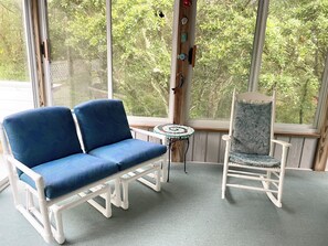 Een kamer met een blauwe bank en een gestreepe fauteuil, met uitzicht op groen.