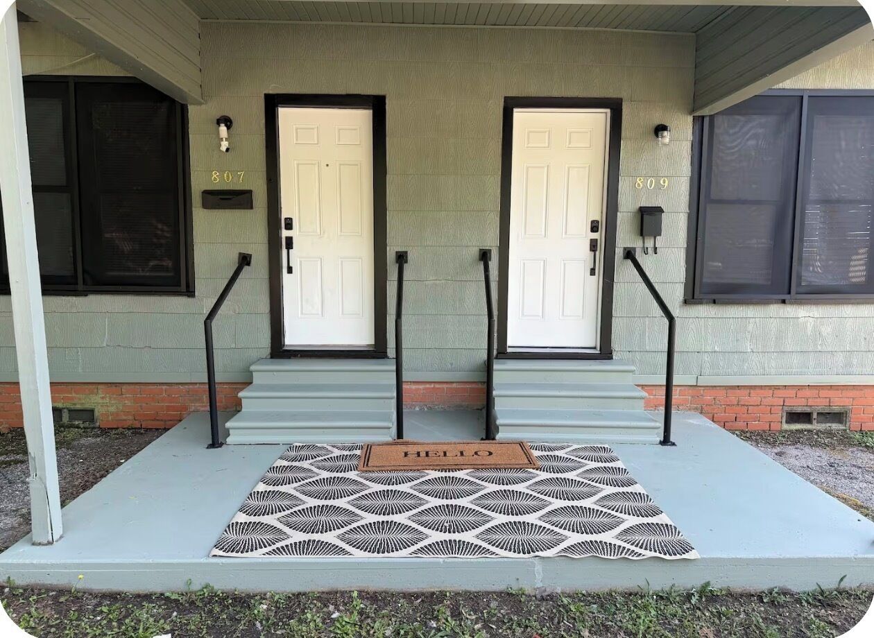 A two-door entrance with a 'HELLO' mat, numbered doors 807 and 809, and a small mailbox.