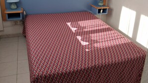 Un dormitorio con una cama, dos mesitas de noche, una lámpara, un cuadro en la pared y una ventana.