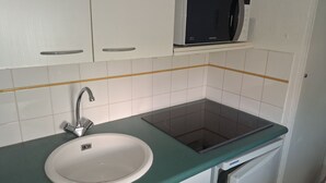 Una cocina con un lavabo blanco, un grifo de acero inoxidable, un microondas y un horno empotrado.