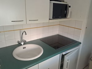 Eine Küche mit weißem Spülbecken, Armatur aus Edelstahl, Mikrowelle und eingebautem Backofen.