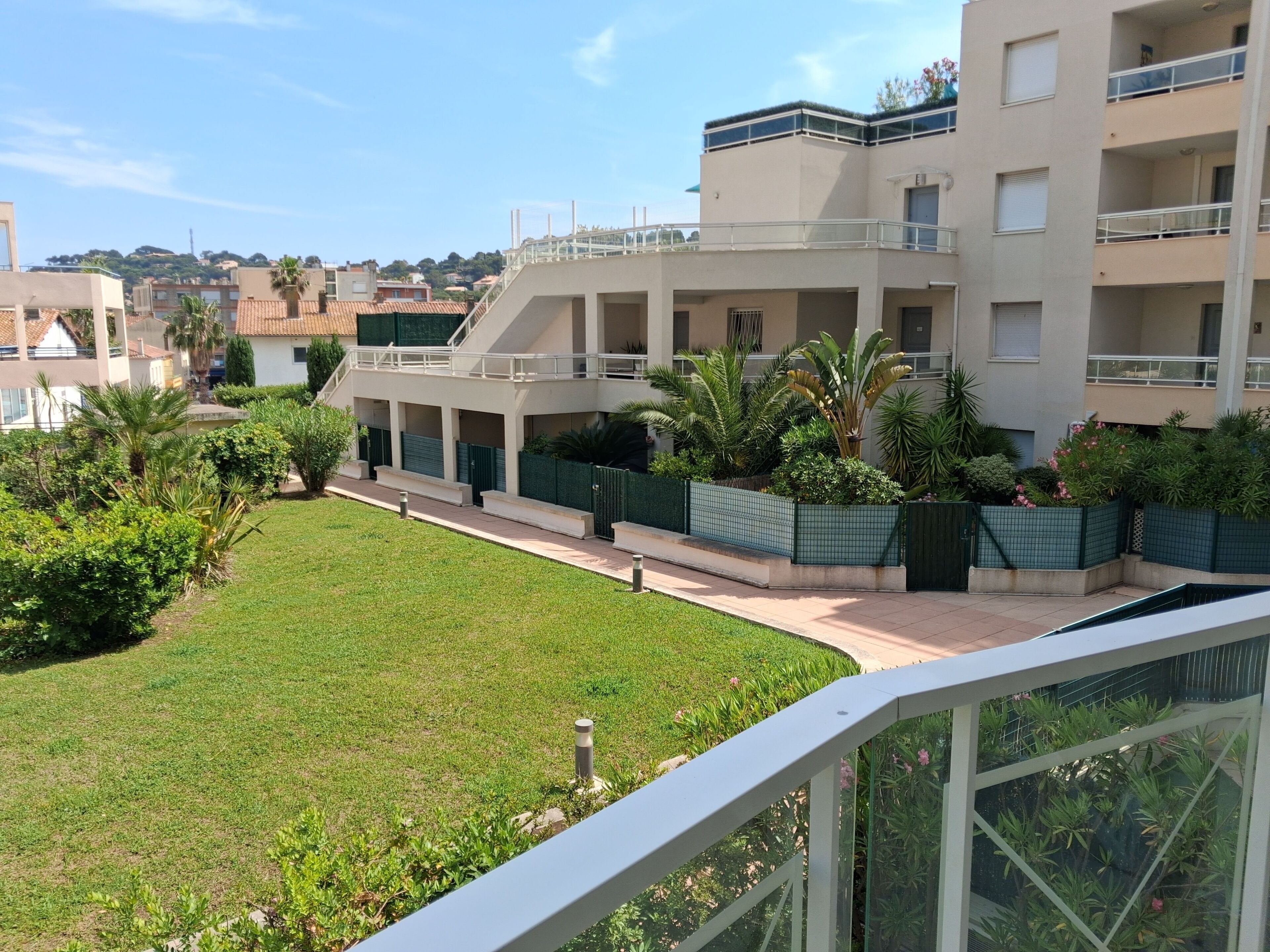 Un edificio residencial con varios balcones, un césped bien cuidado y una variedad de plantas.