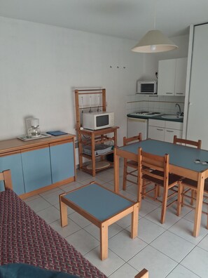 Una cocina compacta con microondas, cafetera y una mesa de comedor con sillas.