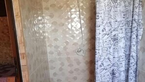 Un baño con ducha, lavamanos y cortina de ducha estampada.