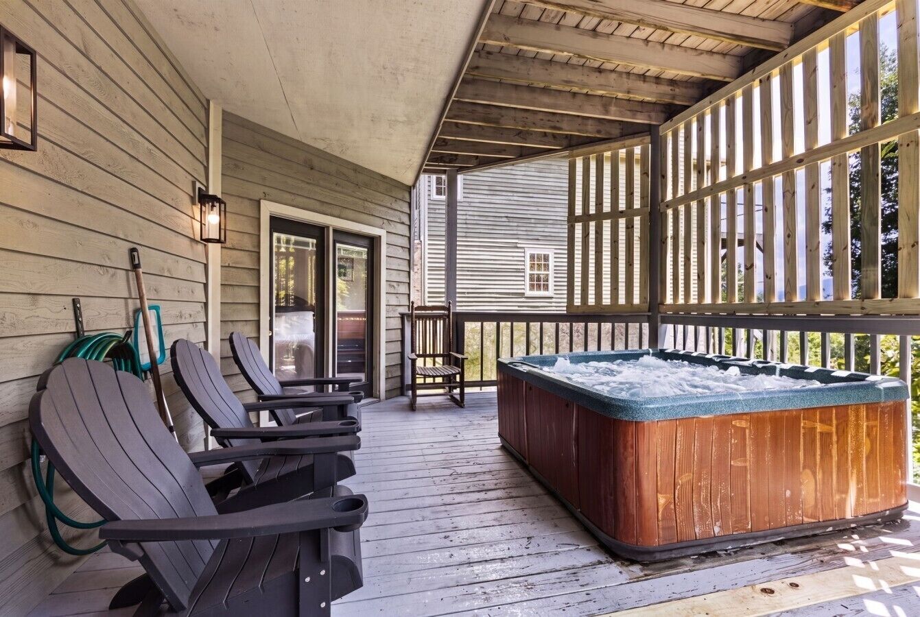 A wooden deck with Adirondack chairs and a hot tub.