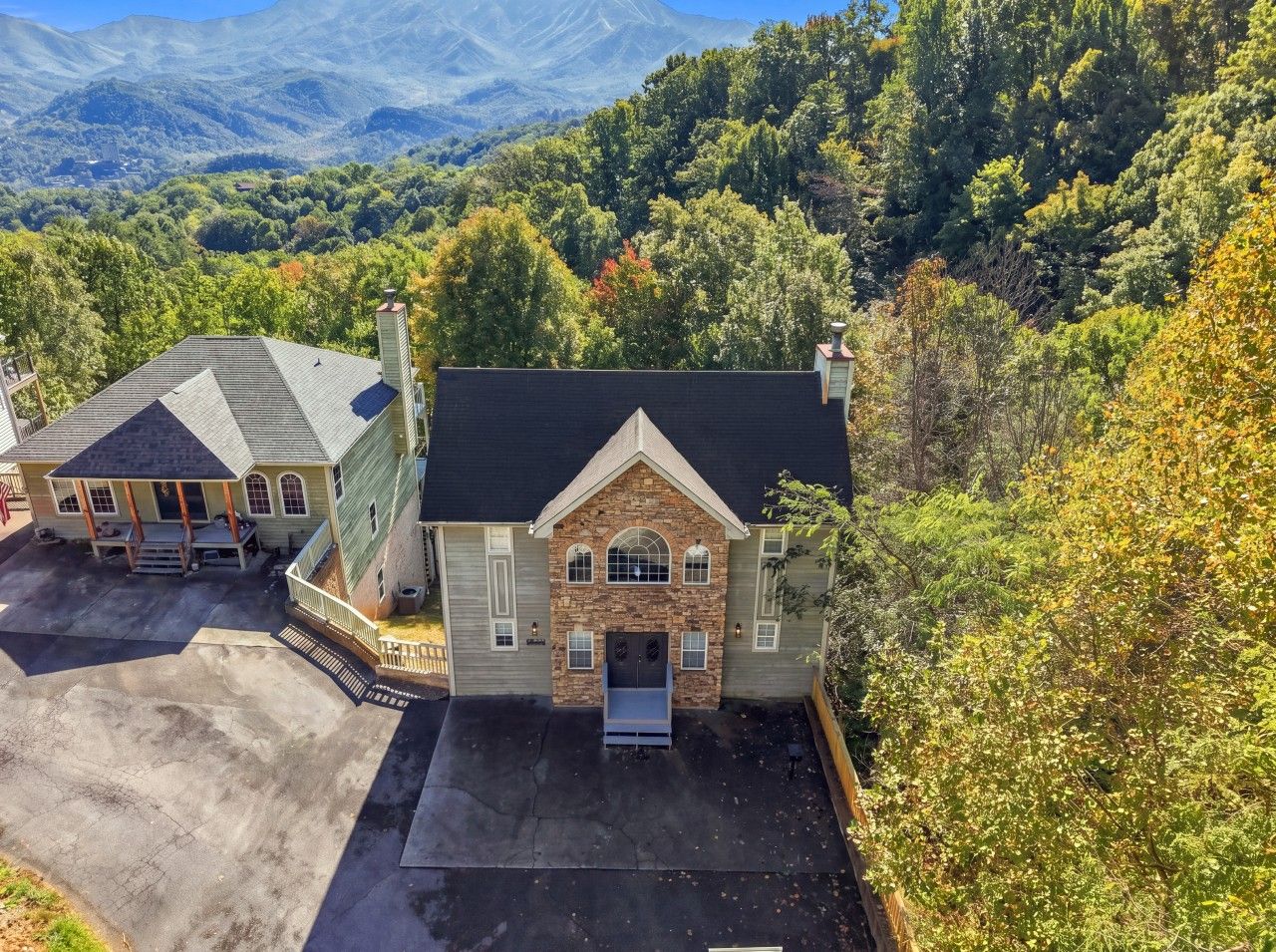 A two-story house with a stone facade, a front porch, and a driveway.