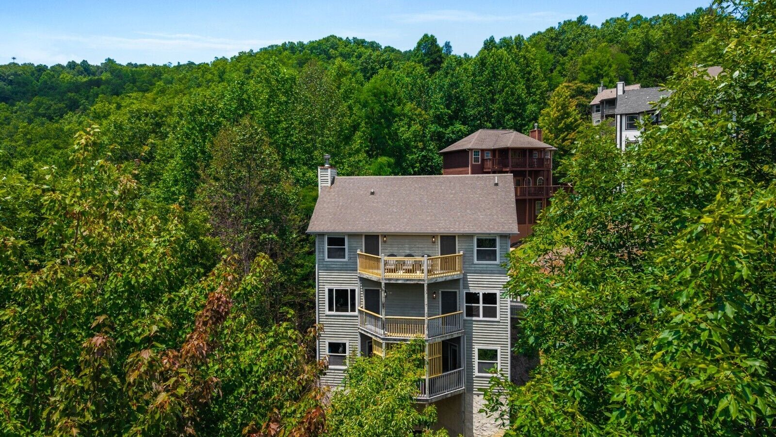 A multi-story building with balconies, surrounded by dense greenery.