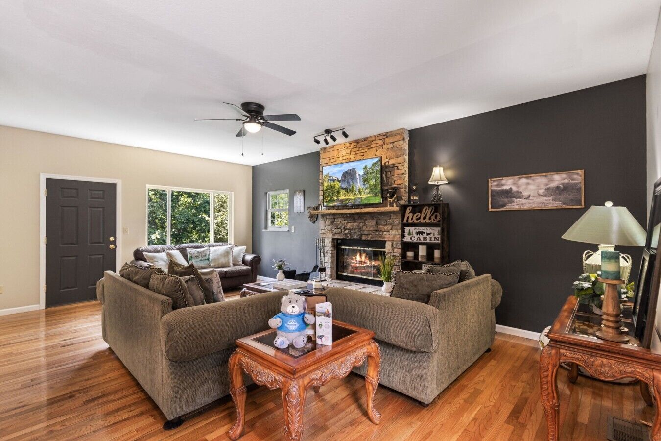 A living room with a fireplace, two sofas, a coffee table, and a ceiling fan.