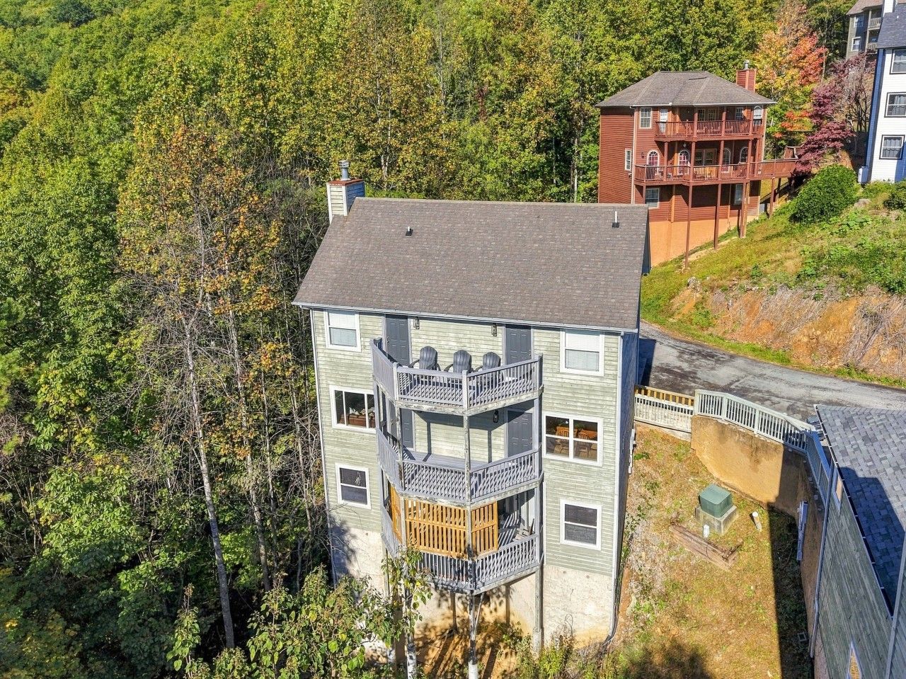 A multi-story building with a balcony on the second floor, surrounded by trees.