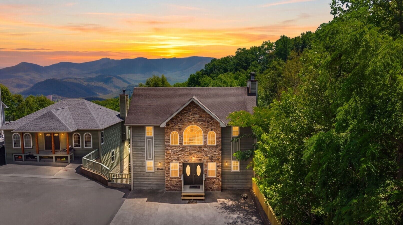 A two-story house with a stone facade, a front porch, and a driveway.
