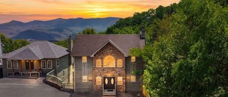A two-story house with a stone facade, a front porch, and a driveway.