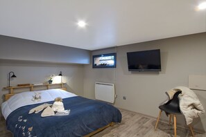 A bedroom with a bed, two bedside lamps, a TV, a chair, and a radiator. - Chalet rénové à 150 m du télésiège | Vue montagne (Mont-de-Lans)