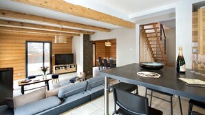Ein modernes Interieur mit Essbereich, einer Couch, einem Fernseher und einer Champagnerflasche.