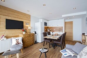Ein kompakter Wohnraum mit Essbereich, Küchenzeile und einer gemütlichen Sitzecke mit Sofa und Sesseln.